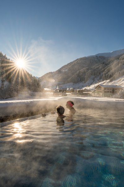 Frau im Infinity Pool blickt ins Grüne im Hotel Tuxertal